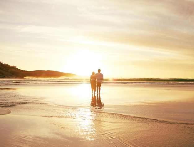 El autocontrol es para los acaparadores. Vista trasera de una pareja irreconocible disfrutando de un romántico paseo por la playa.