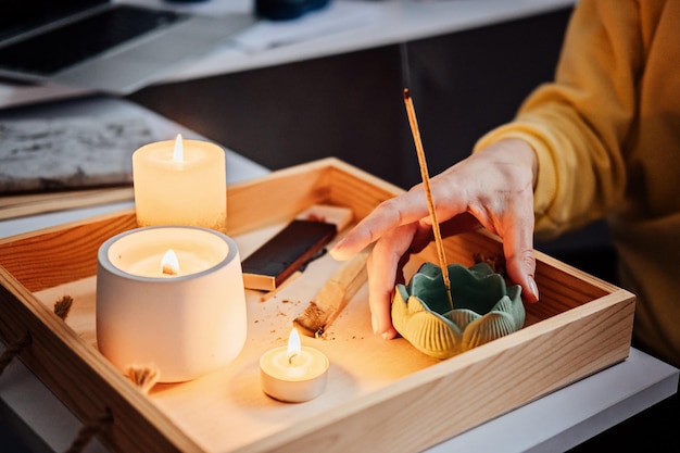 Autocuidado salud mental Mujer joven sentada cerca de la mesa con velas encendidas Aroma Sticks disfrutar de la meditación en casa Sin estrés hábito saludable atención plena estilo de vida concepto de alivio de la ansiedad