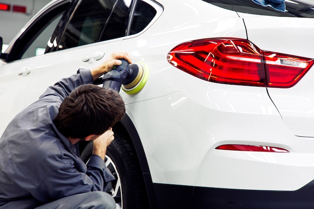 Autodetails - Hände mit Orbitalpolierer in der Autowerkstatt