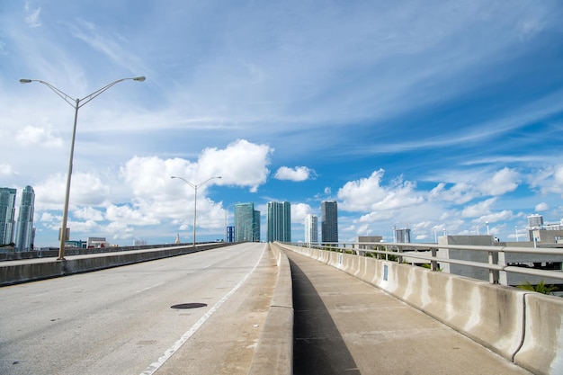 Autoestrada de Miami ou estrada pública para veículos de transporte e arranha-céus urbanos em fundo de céu azul nublado ao lado do porto miami dade