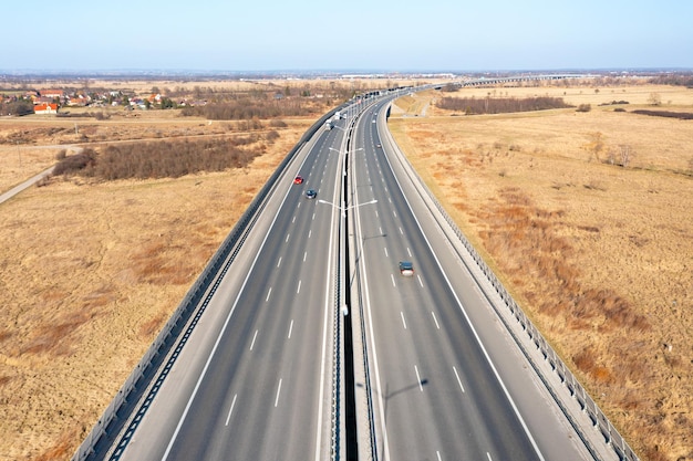 Autoestrada recuando na distância e campos amarelos nas laterais