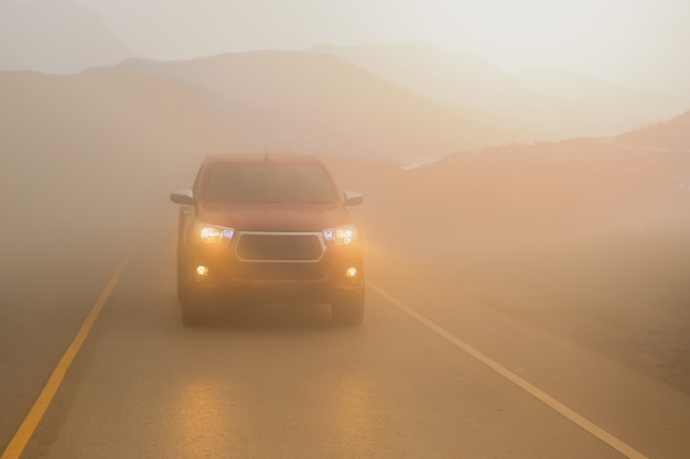 Autofahren im nebelberg mit scheinwerferstrahlen im dichten nebel.