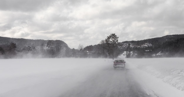 Autofahren im Winterblizzard auf verschneiter Straße in Norwegen