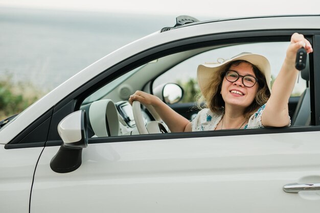 Autofahrer Frau lächelnd zeigt neue Autoschlüssel und Auto Weibliches Fahren gemietetes Cabrio in den Sommerferien