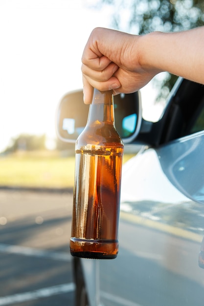 Autofahrer hält eine Flasche Bier