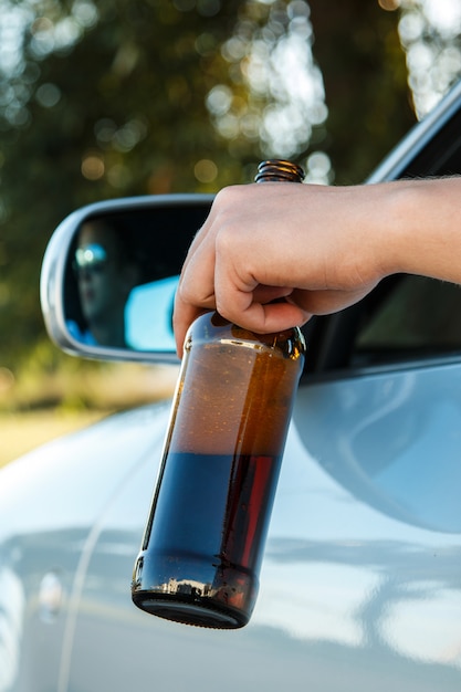 Autofahrer hält eine Flasche Bier