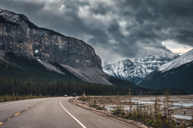 Autofahrt auf der Autobahn mit stimmungsvollem Himmel auf felsigen Bergen im Banff-Nationalpark