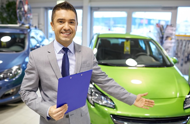 autogeschäft, autoverkauf, konsum und menschenkonzept - glücklicher mann auf der autoshow oder im salon