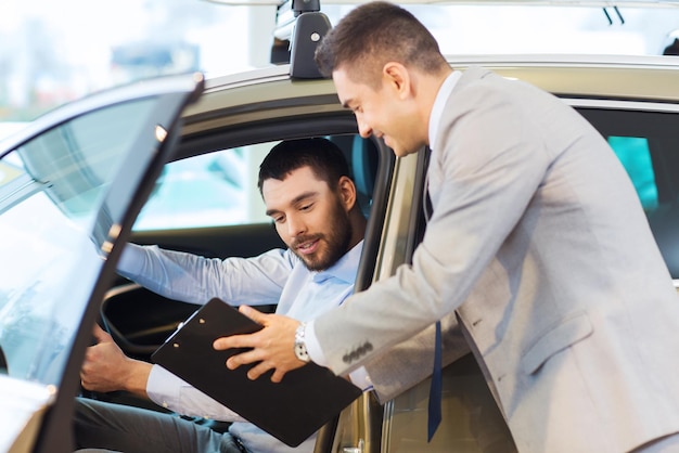 autogeschäft, autoverkauf, konsum und personenkonzept - glücklicher mann mit autohändler in autoshow oder salon