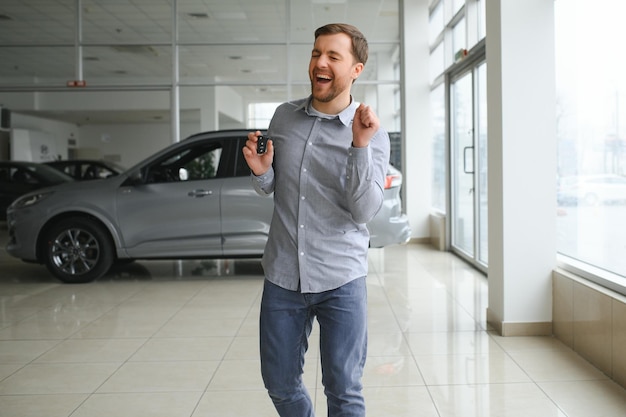 Foto autohaus besuchen schöner bärtiger mann streichelt sein neues auto und lächelt