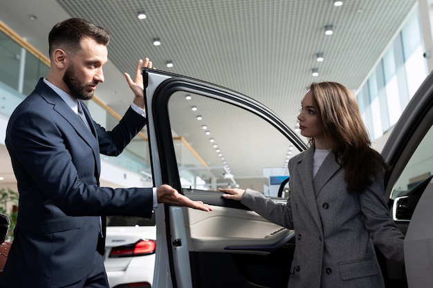 Autohausberater, der einer jungen Frau ein neues Auto vorstellt