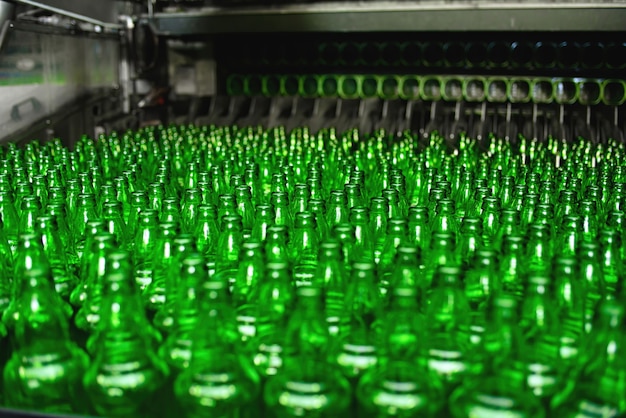 Automatisierte Förderstrecke in einer Brauerei. Reihen von grünen Glasflaschen auf der Nahaufnahme des Förderers.