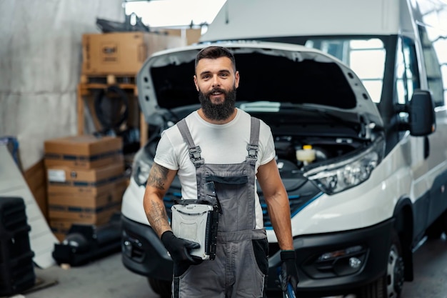 Un automecánico con equipo en el taller sonriendo a la cámara