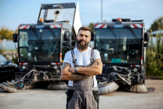 Un automecánico exitoso parado afuera con los brazos cruzados y mirando la cámara