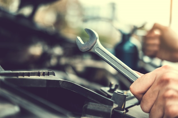 Foto automechaniker, der im garagentechniker hands des automechanikers arbeitend in der autoreparatur service- und wartungsautokontrolle.