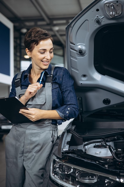 Automechaniker der jungen Frau, der Auto am Autoservice überprüft