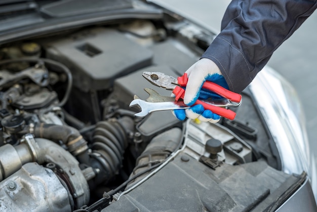 Automechaniker, der mit Schlüsselschlüssel in der Autoreparatur arbeitet, Nahaufnahme