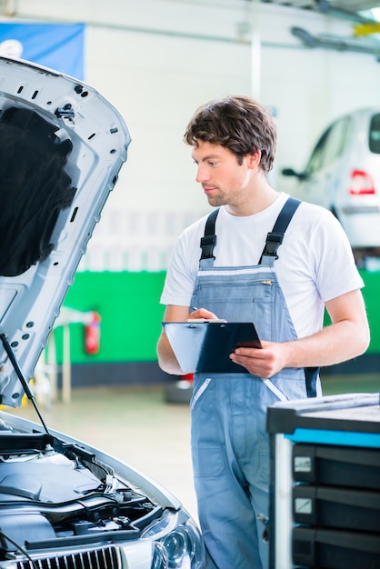 Foto automechaniker, der mit werkstatt in werkstatt arbeitet