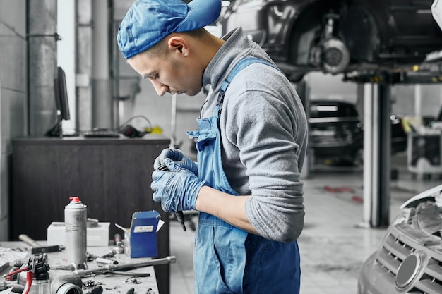 Automechaniker, der nahe Tisch mit verschiedenen Werkzeugen arbeitet