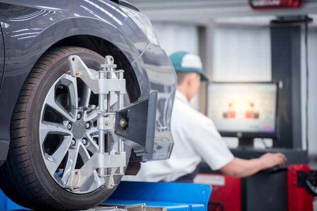 Automechaniker, der Sensor während der Suspendierungsjustage installiert. Achsvermessungsarbeiten an der Reparaturwerkstatt