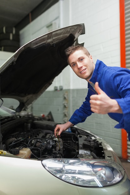 Automechaniker durch Auto Daumen oben gestikulierend