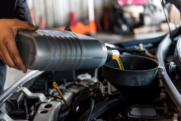 Automechaniker füllt ein frisches Schmiermittel Motoröl