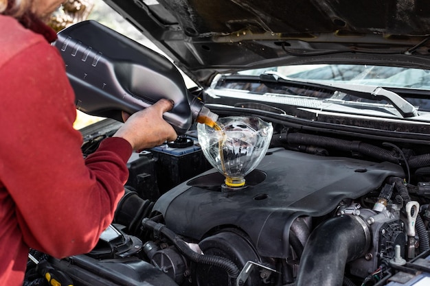 Automechaniker gießt motoröl durch den trichter in den automotor ölwechsel  im auto