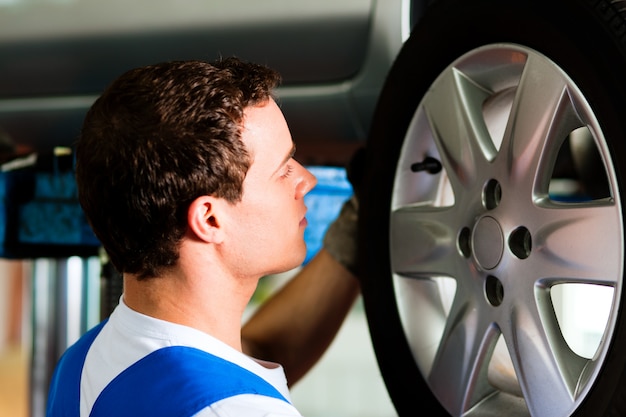 Automechaniker in änderndem reifen der werkstatt