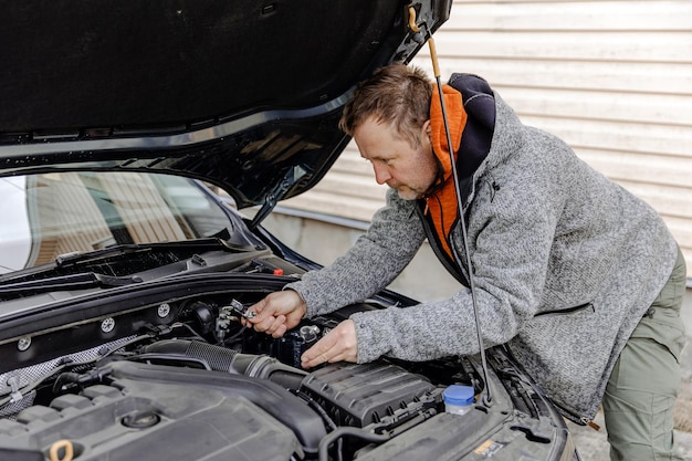 Automechaniker kaukasischer weißer Mann, der in einer Autowerkstatt arbeitet Einbau der neuen Batterie unter der Motorhaube