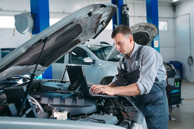 Automechaniker mit einem Computer-Laptop zur Diagnose und Überprüfung des Automotors