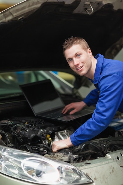 Automechaniker mit Laptop Maschine überprüfend