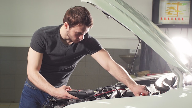 Automechaniker testet elektrisches System am Automobil.