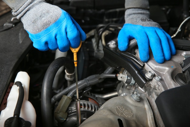 Automechaniker zieht den Ölmessstab das Öl aus dem Motor des Autos