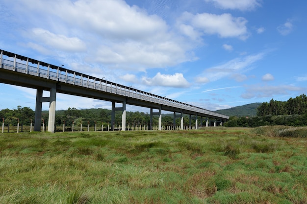 Automobilbrücke über eine grüne Wiese gegen eine Ansicht des blauen Himmels unten