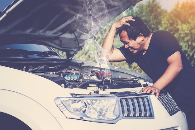 un automóvil averiado, motor abierto y fumar