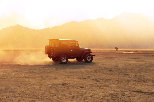 Un automóvil se está ejecutando en el desierto campo a través de la mañana. Vida de aventura al aire libre