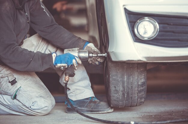 Automóvil, mecánico de automóviles, cambio de neumáticos, ruedas del automóvil mediante llave neumática, centro de servicio