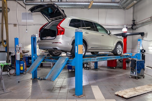 El automóvil usado beige se encuentra en la convergencia de la alineación de las ruedas del soporte del automóvil en el taller para la reparación de vehículos Industria de servicios automotrices