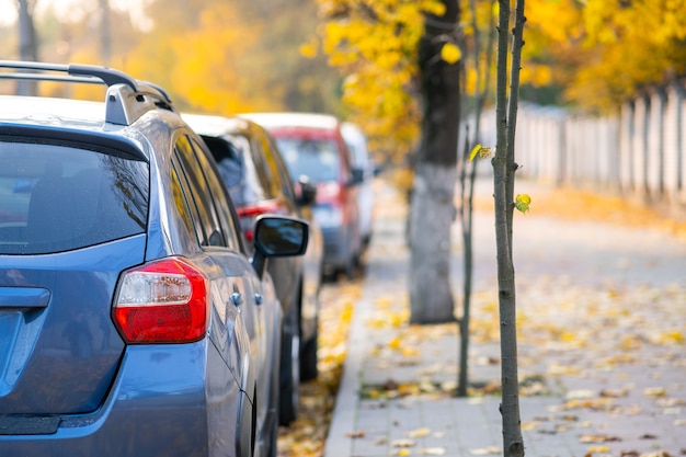 Los automóviles estacionados en una fila en el lado de la calle de la ciudad en un brillante día de otoño.