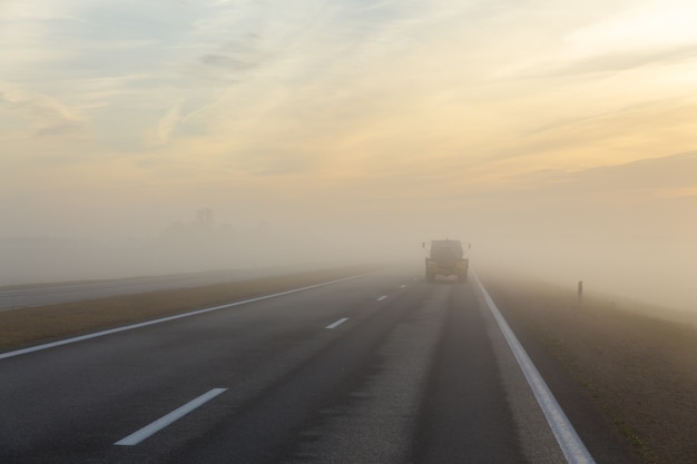 Autopista y coche en niebla.