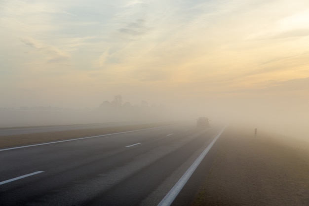 Autopista y coche en niebla.