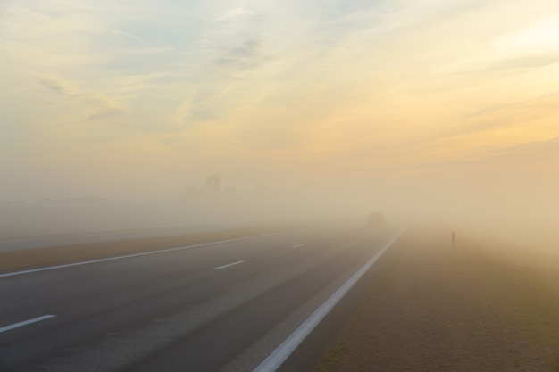 Autopista y coche en niebla.