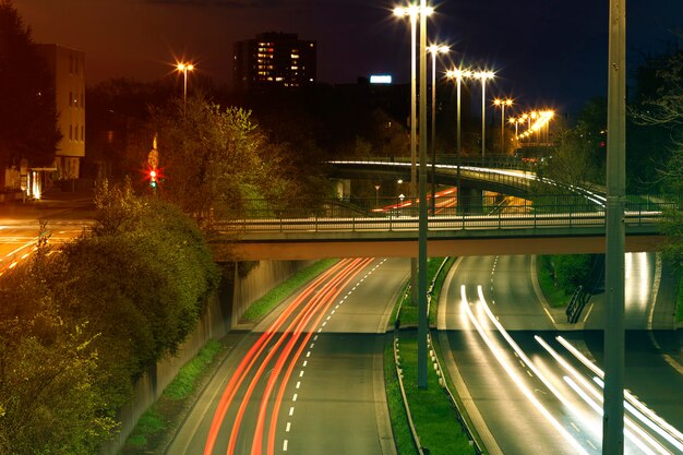 Autopista con tráfico nocturno urbano con enfoque en la carretera. Senderos de autos en una autopista