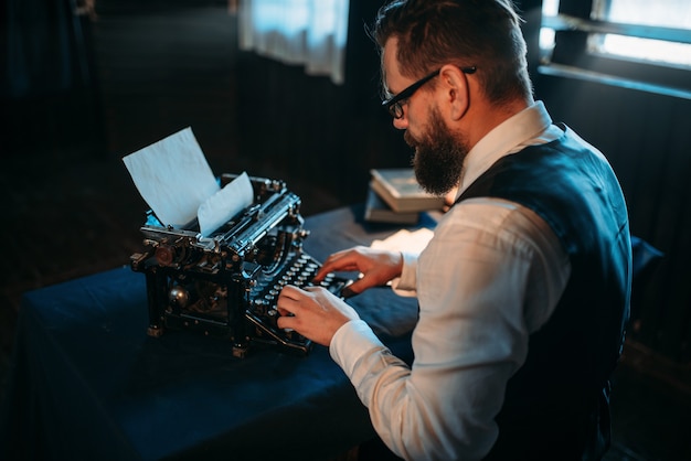 Autor de literatura en gafas escribiendo en máquina de escribir