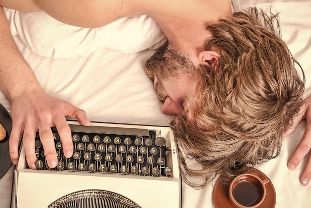 El autor se quedó dormido mientras escribe un libro. El adicto al trabajo se quedó dormido. El hombre con el sueño de la máquina de escribir. Concepto de fecha límite. Trabajó toda la noche.