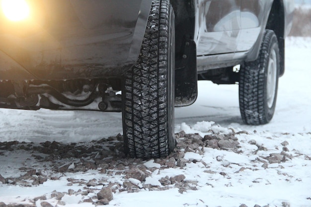 Autorad mit Schnee auf Reifen auf der Winterschotterstraße