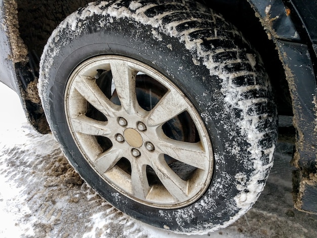 Autorad mit Schnee klebt daran schwarzes Auto steht auf einer schneebedeckten Straße