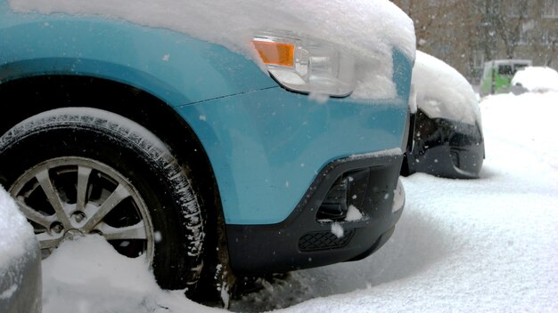 Autoräder stecken in Schneeverwehungen. Rad des blauen Pkw steckt im Schnee fest. Ungünstige Wetterbedingungen.