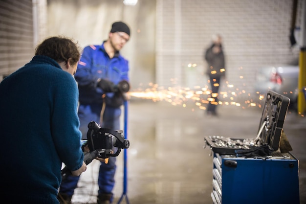 Autoreparaturservice hinter den Kulissen des Schießens, das Wunderkerzen mit einer Schleifmaschine herstellt