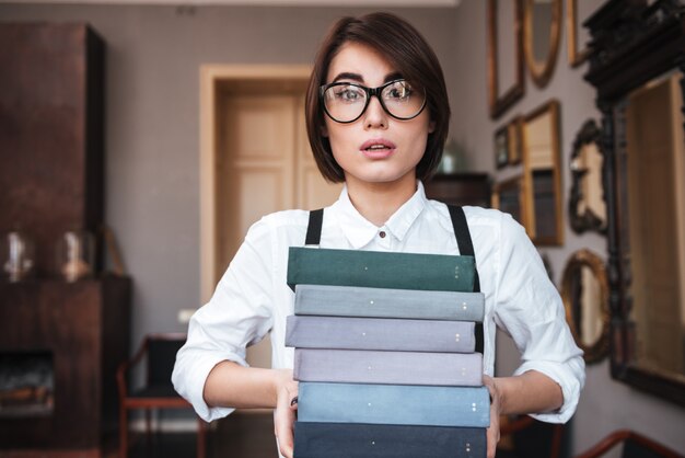 Autorin mit Brille und weißem Hemd, die Bücher in den Händen hält